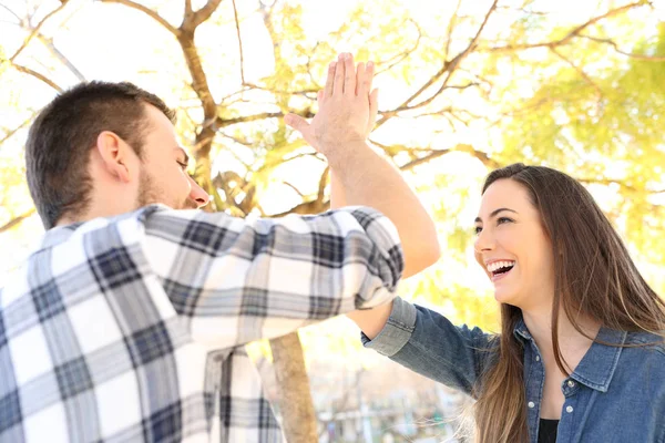Щасливі друзі або пара дає п'ять високих в парку — стокове фото