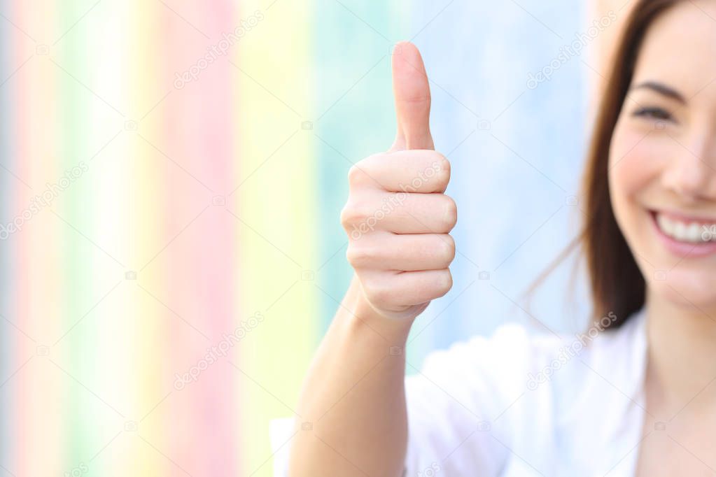 Happy woman gesturing thumbs up in a colorful street