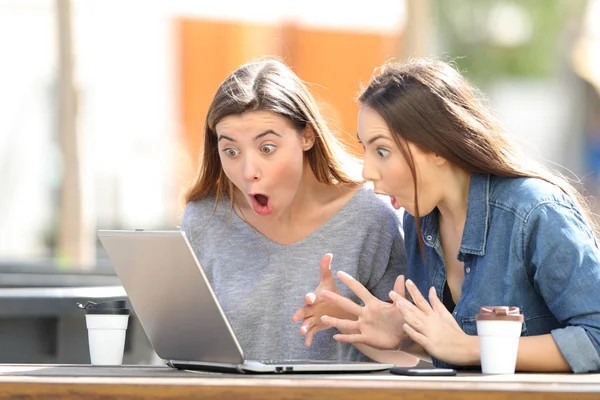 Verbaasd vrienden vinden van on line inhoud op de laptop in een park — Stockfoto