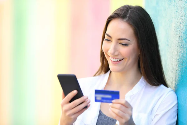 Feliz comprador paga en línea con tarjeta de crédito y teléfono — Foto de Stock