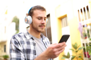 Ciddi adam sokakta yürürken telefonda müzik dinlemek