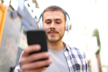 Ciddi adam sokakta yürürken müzik dinlemek önden görünümü