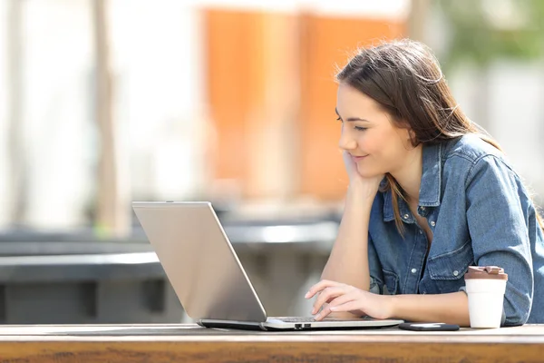 Mulher séria assistindo conteúdo de mídia no laptop em um parque — Fotografia de Stock