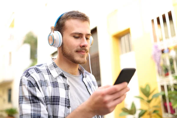 Un bărbat serios care ascultă muzică la telefon mergând pe stradă — Fotografie, imagine de stoc