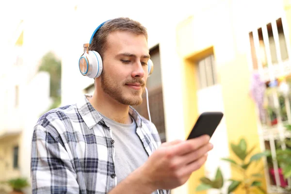 Serious man listening to music on phone walking in the street — Stock Photo, Image