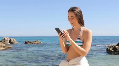 Mutlu kız bikini plaj akıllı telefon tatile kontrol