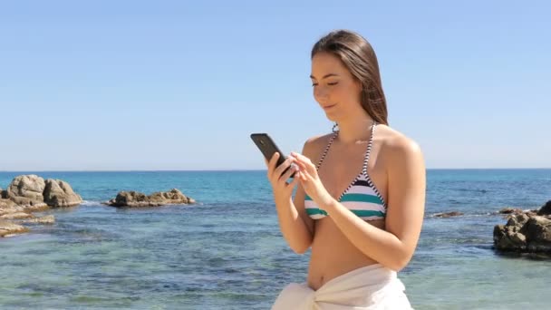 Ευτυχισμένος Κορίτσι Στο Μπικίνι Έλεγχος Έξυπνο Τηλέφωνο Στην Παραλία Στις — Αρχείο Βίντεο