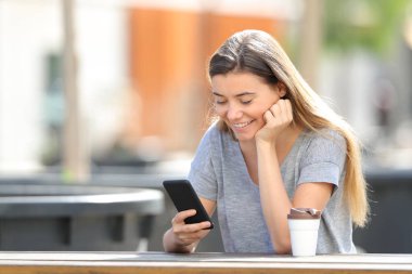 Bir parkta oturan bir akıllı telefon kullanarak mutlu genç kız