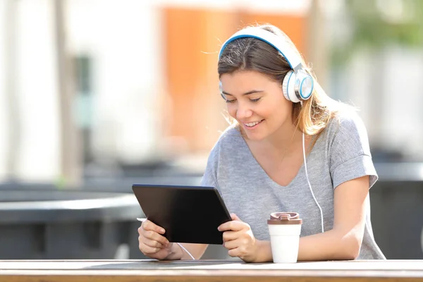 Glückliches Teenager-Mädchen, das im Park mit Tablet Musik hört — Stockfoto