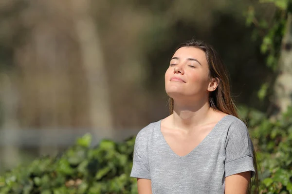 Розслаблена дівчина дихає свіжим повітрям у парку сонячний день — стокове фото