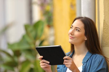 Yan görünümlü bir tablet düşünme tutan kadın