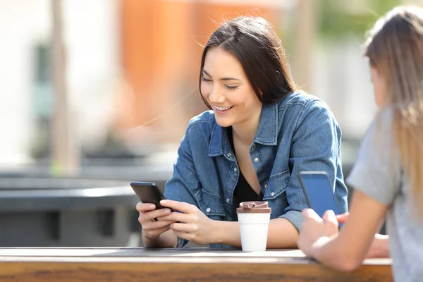 Women using their smart phones in a park — Stock Photo, Image