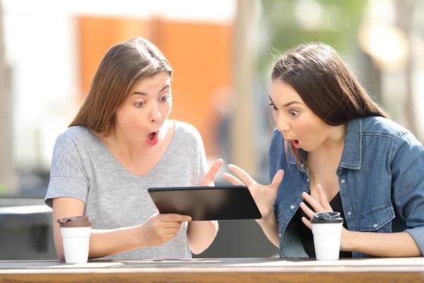 Dos amigos asombrados viendo los medios en una tableta — Foto de Stock