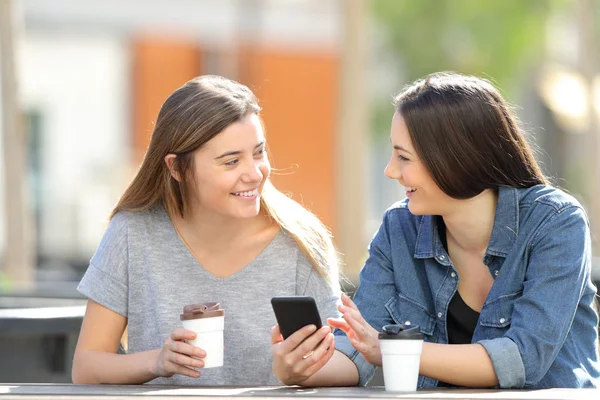 Twee vrienden die over telefoon inhoud in een park spreken — Stockfoto