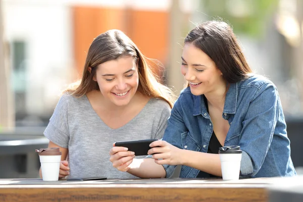 Dos mujeres felices viendo los medios en el teléfono inteligente —  Fotos de Stock