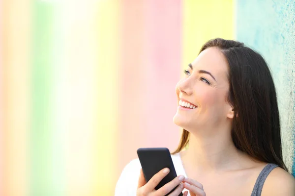 Happy Girl Holding telefoon denken kijken naar Side — Stockfoto