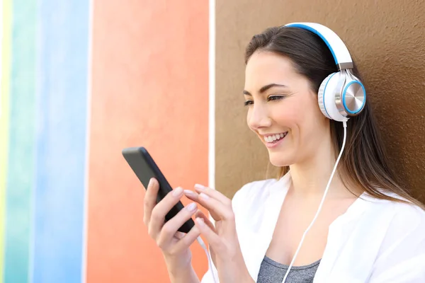 Lycklig kvinna lyssnar på musik med hjälp av telefon utomhus — Stockfoto