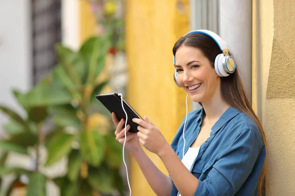 Happy Girl luisteren Tablet inhoud kijkt naar je — Stockfoto