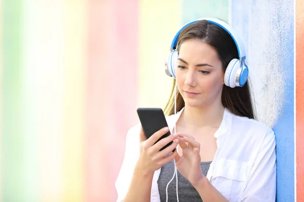 Seriös kvinna lyssnar på musik med hjälp av telefon utomhus — Stockfoto