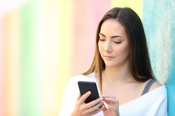 Vážná žena používající chytrý telefon v barevné stěně — Stock fotografie