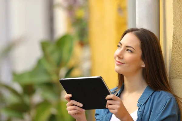 Kobieta trzyma tablet myślenia patrząc na bok — Zdjęcie stockowe