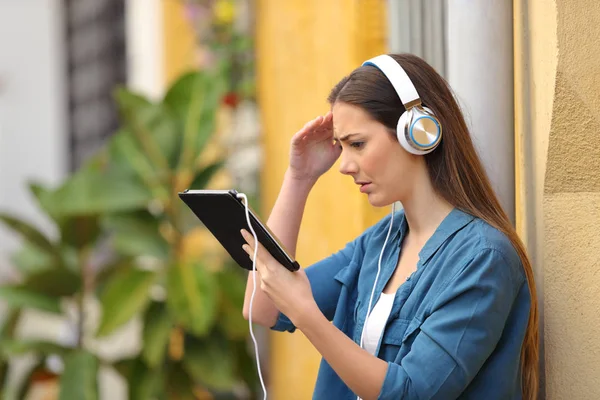 Worried girl listening and watching tablet content — Stock Photo, Image