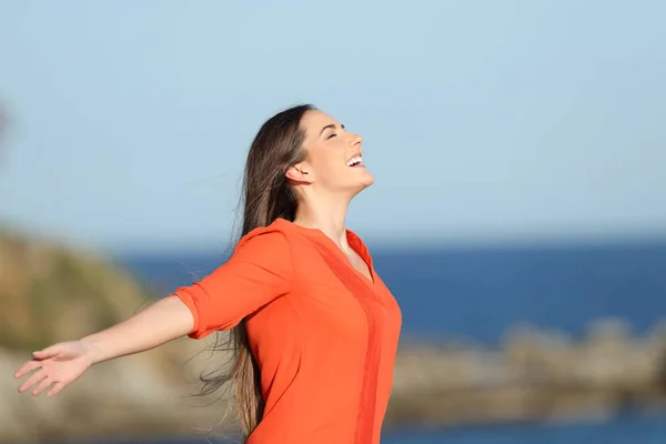 Donna felice in arancione respirando aria fresca nella costa — Foto Stock