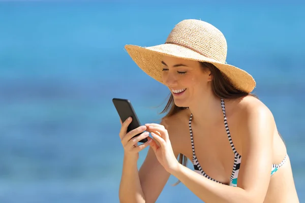 Gelukkig toeristische met behulp van slimme telefoon op het strand op vakantie — Stockfoto