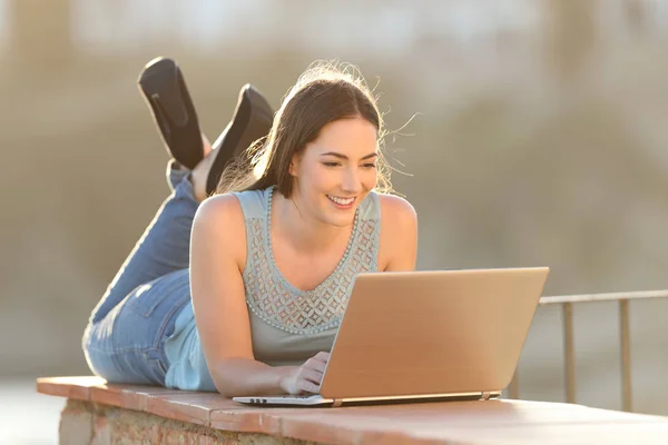 Šťastná žena na přenosném počítači ležící na zeď terasy — Stock fotografie