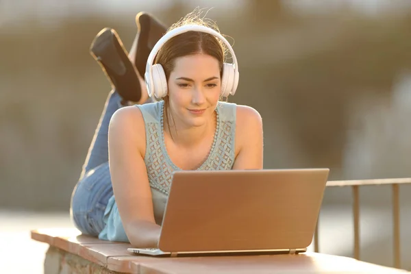 Donna che indossa cuffie guardare i media sul computer portatile — Foto Stock