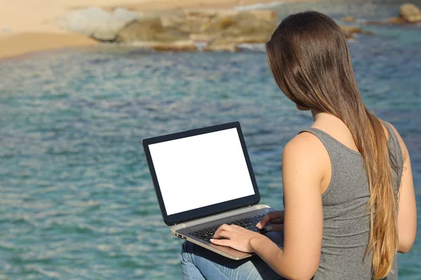 Mujer usando laptop mostrando pantalla en blanco en la playa — Foto de Stock