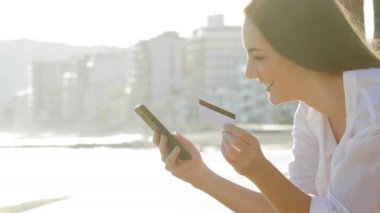 Yan görünümü ile kredi kartı ve sahilde akıllı telefon ödemek bir kadın portresi
