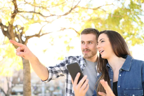 Paar praten en wijzen weg bedrijf slimme telefoon — Stockfoto