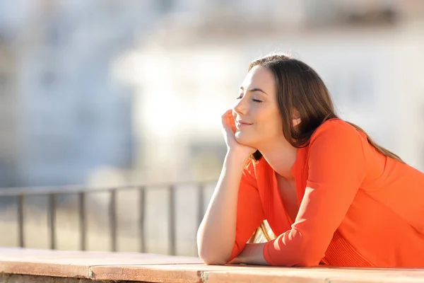 Щаслива жінка в помаранчевому роздумах на балконі — стокове фото
