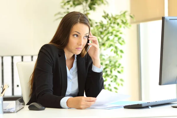 Заплутана бізнес-леді розмовляє по телефону в офісі — стокове фото