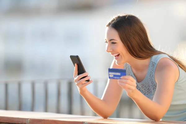 Ενθουσιασμένος κορίτσι πληρώνει με πιστωτική κάρτα και το τηλέφωνο — Φωτογραφία Αρχείου
