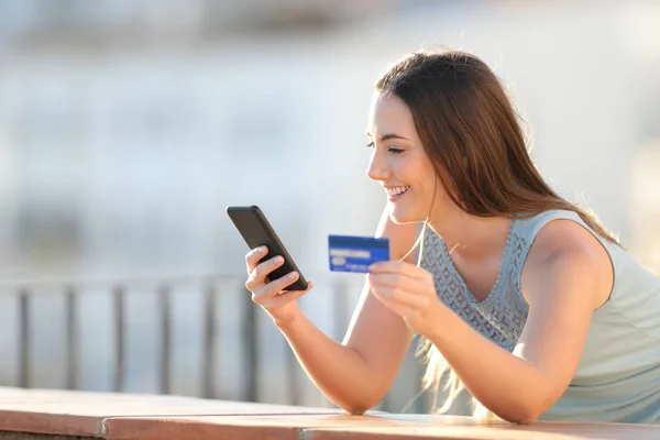 Menina feliz está pagando com cartão de crédito e telefone — Fotografia de Stock