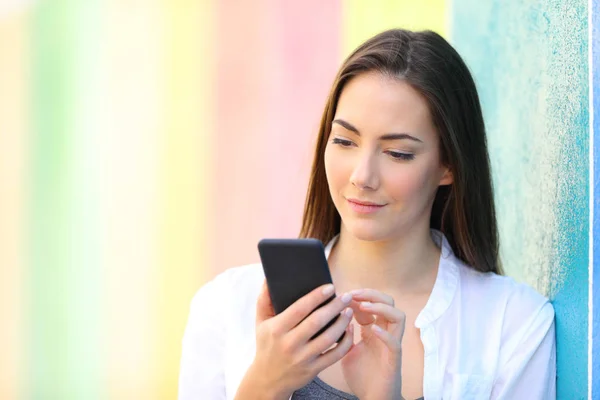 Chica comprobando el teléfono inteligente en una calle colorida — Foto de Stock