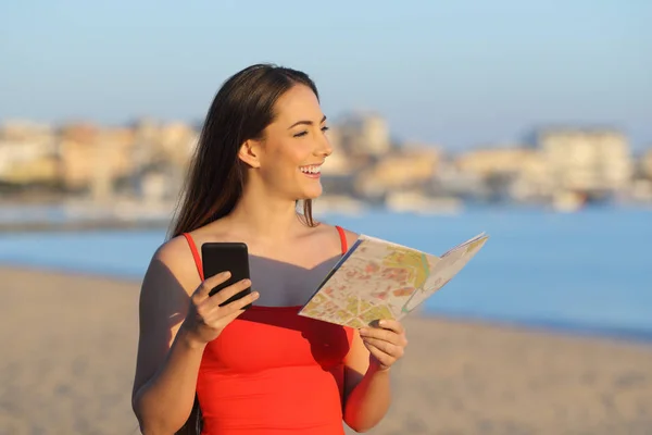 Happy Tourist gospodarstwa mapy i telefon kontemplacji plaży — Zdjęcie stockowe