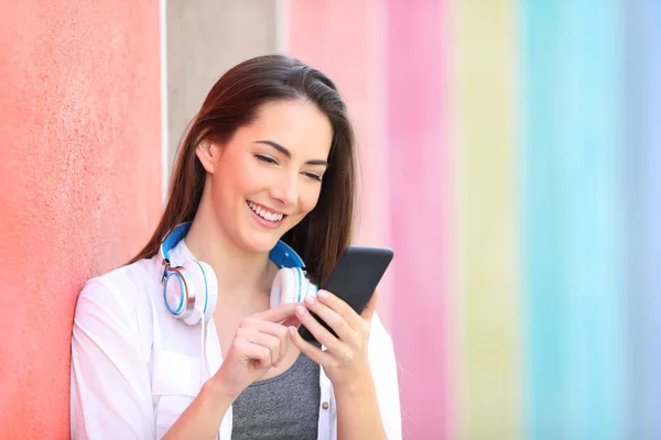 壁に寄りかかっているスマートフォンを使った幸せな女性 — ストック写真