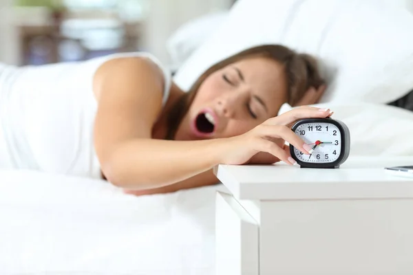 Woman yawning at wakeup turning off alarm clock — 스톡 사진