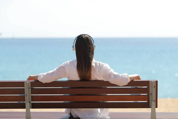 Back View av en kvinna som lyssnar på musik på stranden — Stockfoto