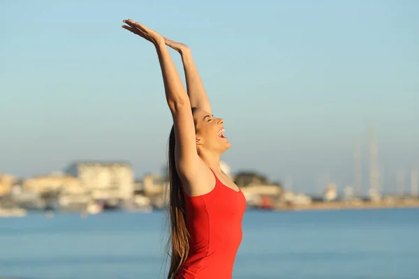 Excited girl in red celebrating vacation on the beach — Stock Photo, Image