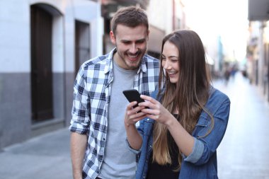 Mutlu çift sokakta cep telefonu kullanarak yürüyüş