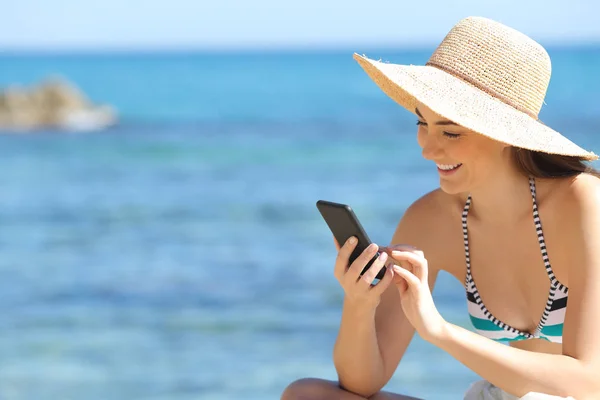 Turista feliz verificando telefone inteligente na praia — Fotografia de Stock