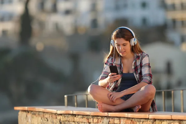 Adolescenti che ascoltano musica seduti su un cornicione in vacanza — Foto Stock