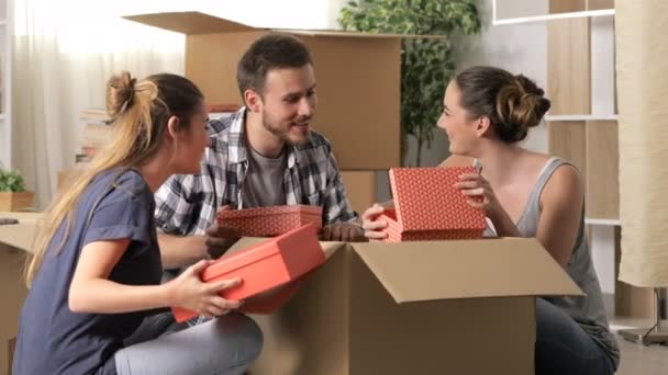 3人の幸せなルームメイトが家に引っ越して箱から出す持ち物は一緒に働く — ストック動画
