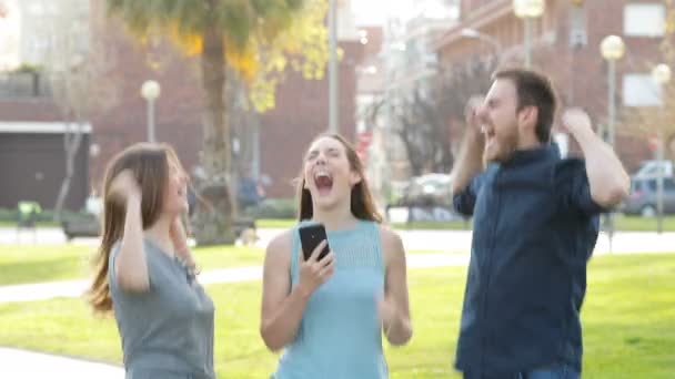 Upphetsad Vänner Hoppar Gatan Efter Att Kontrollerat Smart Telefoninnehåll — Stockvideo