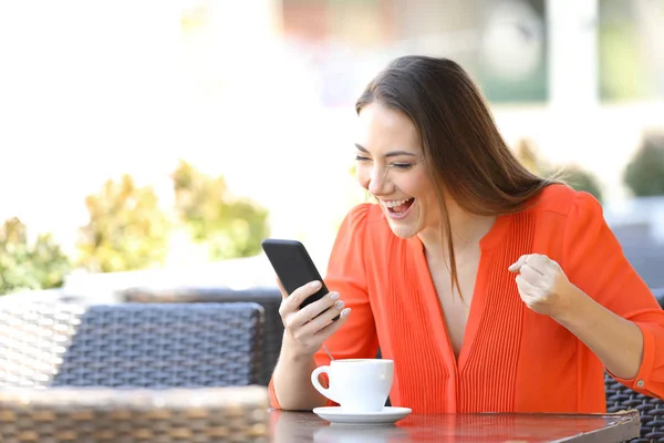 Upphetsad kvinna kontrollera Smart telefoninnehåll i ett kafé — Stockfoto