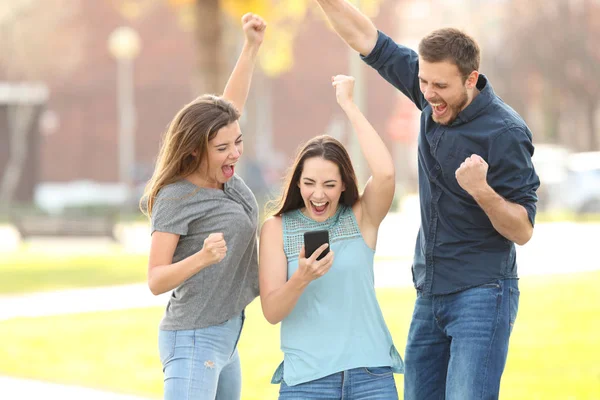 3 amigos emocionados saltando lectura buena netw en el teléfono —  Fotos de Stock